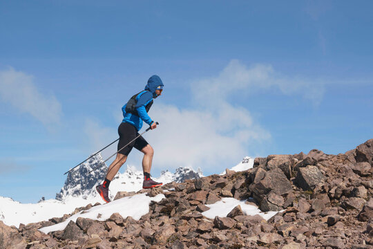 Trail runner ascends a rocky and snowy mountain