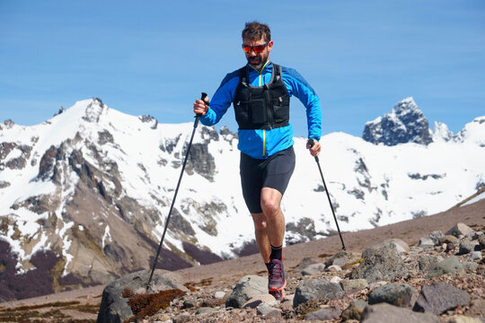 Trail runner ascending a mountain with trekking poles