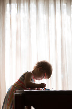 Child at desk near window painting
