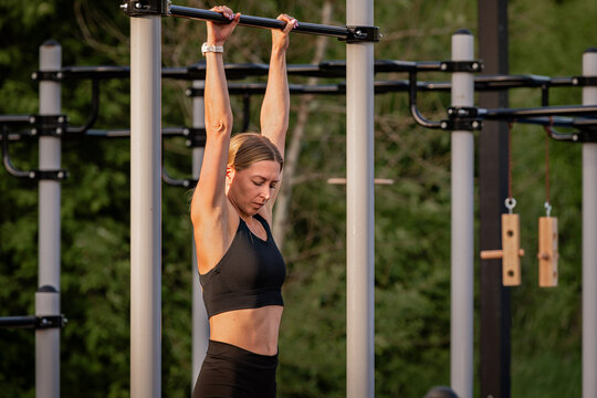 Fit woman hanging from bar at an outdoor gym
