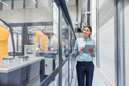 Businesswoman checking robots with digital tablet in high tech company