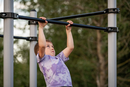 Young boy hanging from monkey bars at a park
