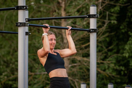 Athletic woman doing pull ups at an outdoor gym