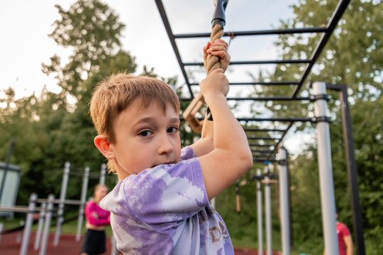 Young boy looks at camera while climbing a rope