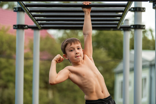 Young boy flexing muscle on outdoor monkey bars