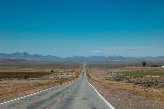 Long empty road stretches toward desert mountains