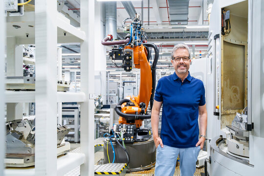 Engineer standing in modern factory with industrial robot