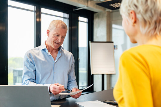 Manager explaining document to colleague during office meeting