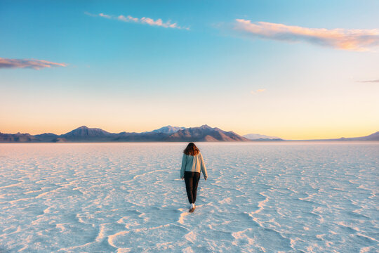 Young woman walking on salt flats at sunset