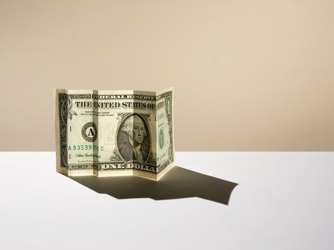 Folded US dollar bill casting a line graph shadow of success