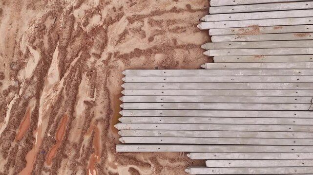 Slow Drone Descent Over Concrete Foundation Piles. Extended aerial shot with a slow downward drone movement above rows of precast concrete piles and orange construction soil.