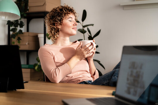 Serene woman enjoying coffee break in tidy modern workspace