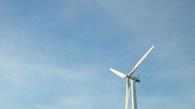 Windmill Spinning Against Blue Sky with Copy Space. A decorative windmill slowly rotates against a bright blue sky while open space remains available for text and branding. The calm motion creates a p