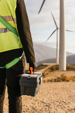 Hand of technician holding toolbox on sunny day