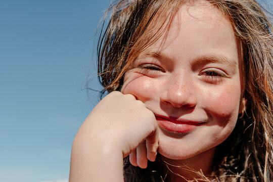 Close-up of girl with hand on chin during sunny day