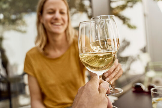 Cheerful woman with man toasting wineglasses in restaurant
