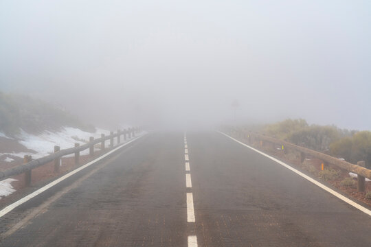 Foggy empty mountain road with snow patches in Tenerife Spain