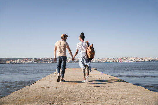 Young couple walking on pier at the waterfront, Lisbon, Portugal