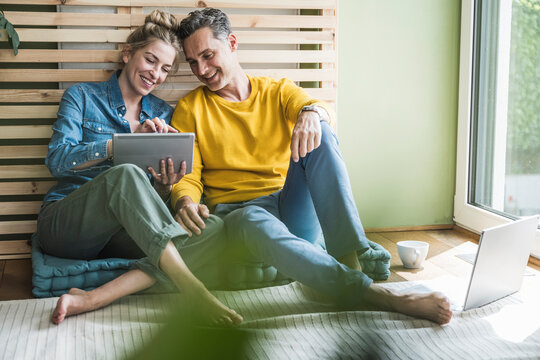 Couple sitting together on mattress using digital tablet