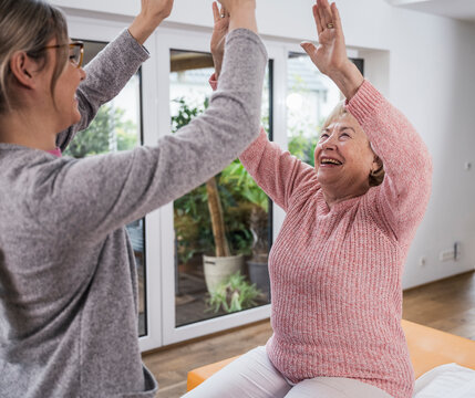 Caregiver and patient high fiving to celebrate success indoors