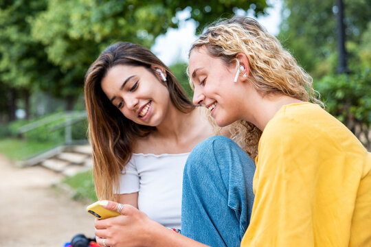 Smiling woman sharing mobile phone with friend in park