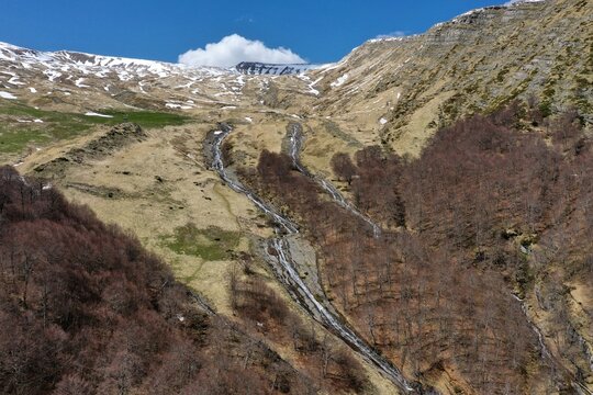 Aerial view of the Cento Fonti di Cesacastina waterfalls cascading down the snow-capped slopes of the Gran Sasso mountains in Crognaleto, Abruzzo, Italy.