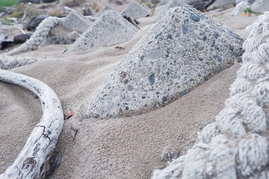 White driftwood and old rope with concrete blocks on the beach
