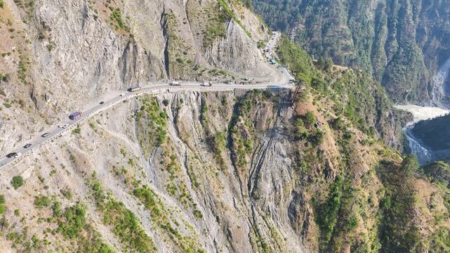 Drone shot of remote logistics trucks stuck on landslide prone highway.