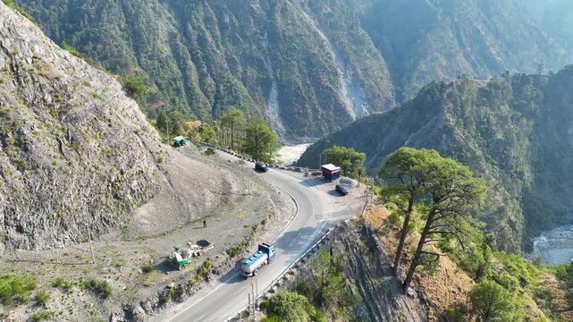 Aerial tracking of blue oil tanker on dangerous Himalayan mountain road.
