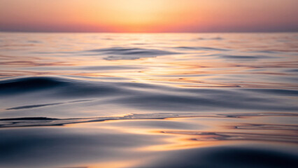 Fototapeta premium Calm ocean waves at sunset with warm light reflection