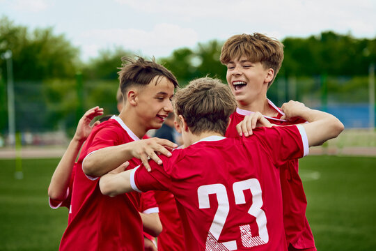 Youth soccer team celebrating together on outdoor field. Concept of junior football victory, school team spirit, youth sports ads and teamwork campaigns.
