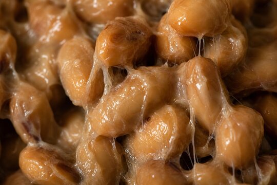 Extreme close-up of fermented soybeans with glossy, stringy mucus coating.