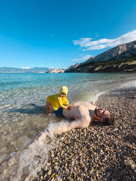 Father and toddler playing on mountain lake beach