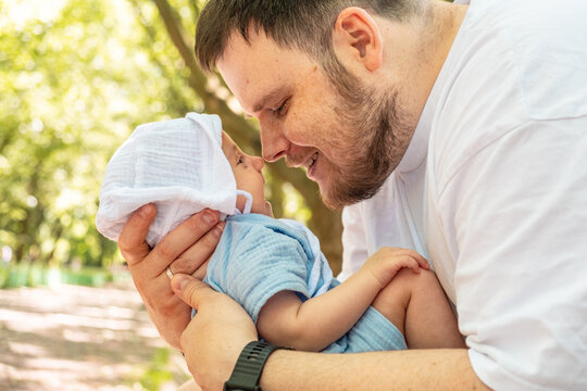 Young father holding baby in sunny park portrait
