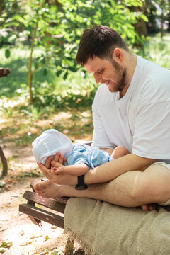 Young father holding baby in sunny park portrait