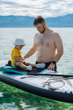 Father and toddler playing on paddleboard in mountain lake