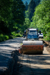 Fototapeta premium Road roller vehicle flattening asphalt at a rural road construction site