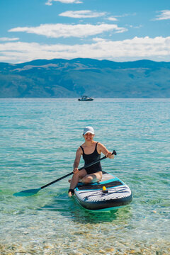 Woman kneeling on paddleboard in mountain lake