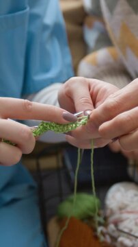 Vertical video of young female caregiver helping senior woman with knitting therapy. Ideal for marketing campaigns focusing on eldercare, nursing homes, and senior well-being