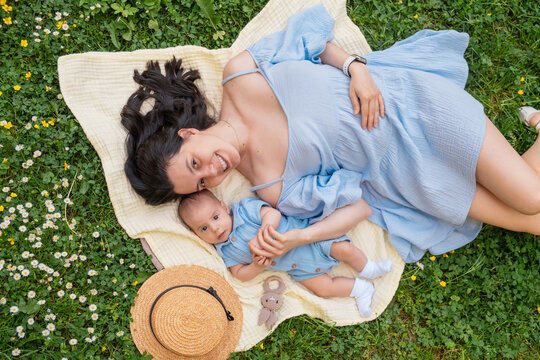 Mother and baby relaxing on blanket in green grass overhead