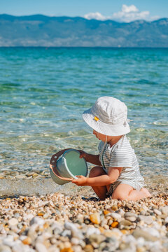 Toddler playing with bucket on clear lake beach