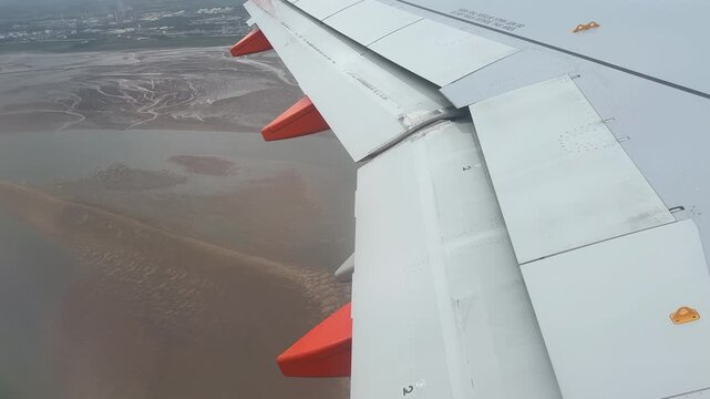 Taking off and flying low in a passenger plane looking out of window at wing and landscape below England UK 4K