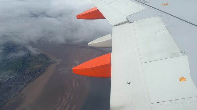 Taking off and flying low in a passenger plane looking out of window at wing and landscape below England UK 4K