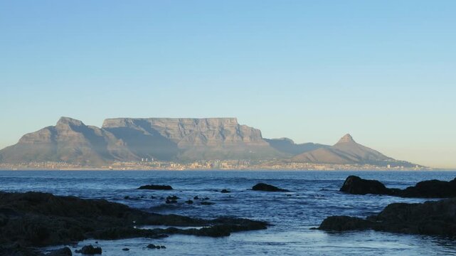 4K 25fps footage from Bloubergstrand showcasing the iconic Cape Town skyline with Table Mountain, Devil&rsquo;s Peak and Lion&rsquo;s Head across Table Bay under clear South African blue skies.