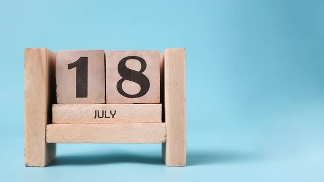 Month of July wooden block calendar on a light blue background