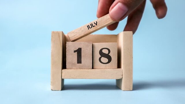 Month of July wooden block calendar on a light blue background