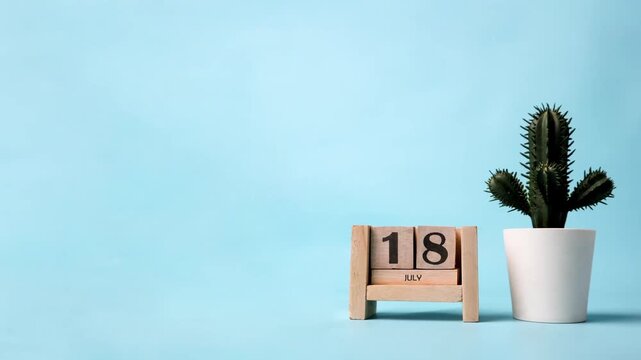 Month of July wooden block calendar on a light blue background