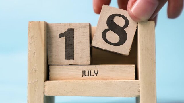 Month of July wooden block calendar on a light blue background