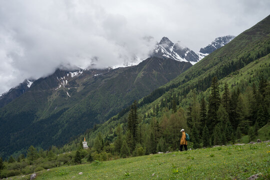 Hikers in the valleys of mist-shrouded snow-capped mountains