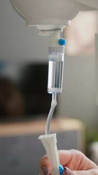 Vertical shot of female nurse adjusting IV drip flow regulator in clinic. Footage healthcare marketing, senior care services, and medical training videos